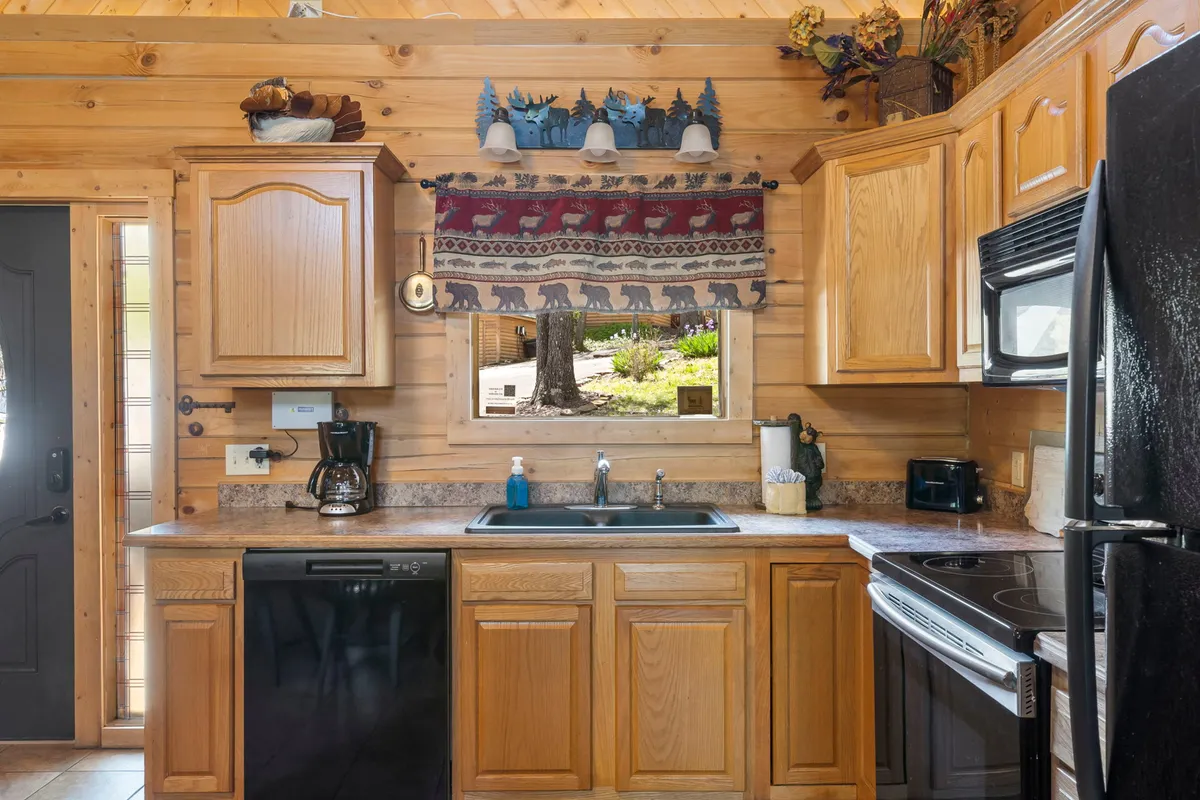 A close-up view of a kitchen sink area with wooden cabinetry and a window, letting in natural light. The countertop is ready for meal prep or gathering over coffee, setting an inviting tone for casual culinary moments.