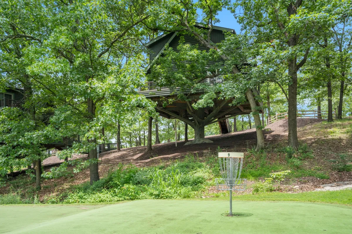 A whimsical treehouse and a disc golf basket sit amid lush greenery, inviting families to play, explore, and spot wildlife. The vibrant outdoor setting highlights both adventure and relaxation.